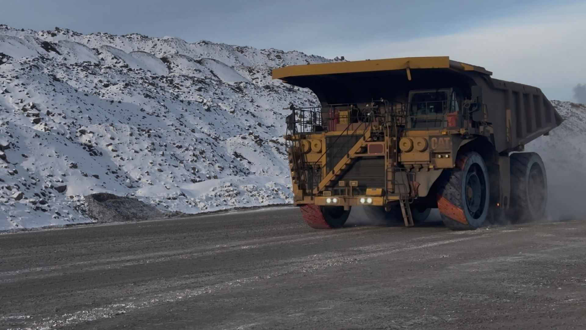 Ultra-class Caterpillar haul truck fitted with ASW units on a snow-covered haul road in sub-zero winter mining conditions
